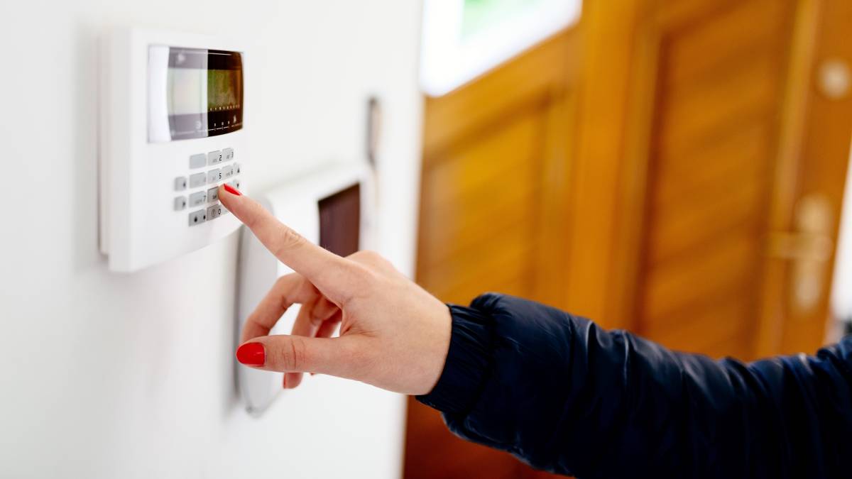 Young woman entering security code on home security alarm system keypad